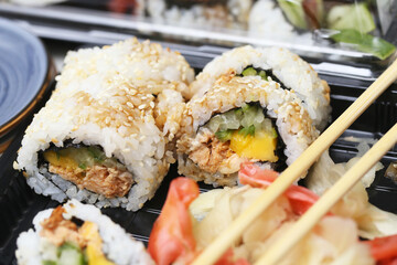 Sushi background. Takeaway box. Wooden chopsticks to eat sushi rolls. Traditional Japanese cuisine fresh ingredients. Plate of sushi seafood, vegetables, and rice. Healthy lunch and delicious meal.