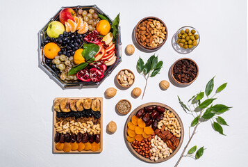 many different trays and bowls with traditional treats for the Tu Bi shvat. top view. white background. flat lay. green branches of the tree.