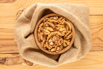 Shelled walnuts with kitchen utensils on a wooden table, close-up, top view.