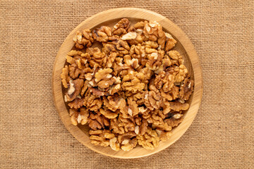 Shelled walnuts with kitchen utensils on jute cloth, close-up, top view.