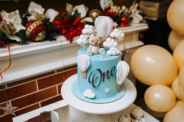 Beautiful blue white decorated cake with cream cupcakes, bear for a child in 1 year birthday in a restaurant. Close-up food photo, candy bar, children's party.