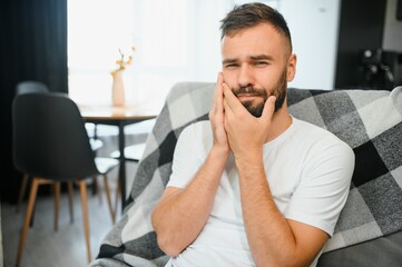 Young man suffering from toothache at home