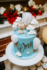 Beautiful blue white decorated cake with cream cupcakes, bear for a child's 1 year birthday. Close-up food photo, candy bar.