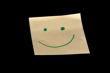 Yellow sticky note on a black background, featuring hand-drawn dots as eyes and an upward-curved line as a mouth, creating a joyful, happy, and calm expression