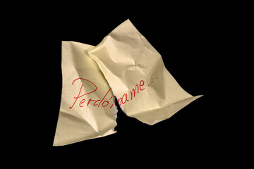 Yellow adhesive paper, similar to a Post-it note, crumpled torn into twi pieces and reassembled like a puzzle, on a black background with the word “Perdóname” in Spanish handwritten in red ink.