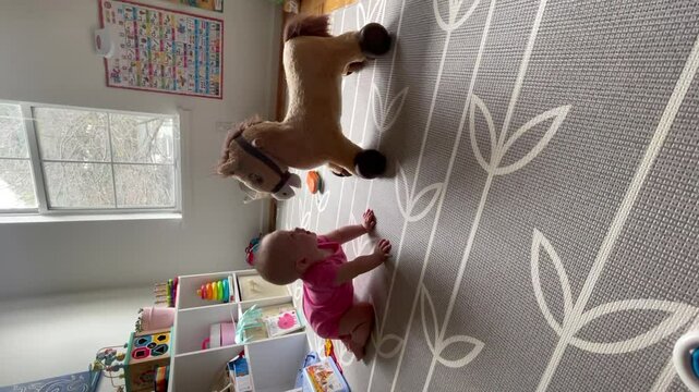 Vertical funny video of a baby playing with a toy horse. Funny baby playing with toys