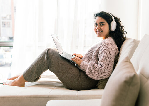 Young latin woman enjoying relaxing time at home with technology