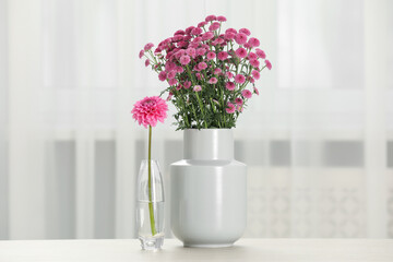 Beautiful pink flowers in vases on table at home