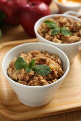 Delicious apple crisp with mint in bowls on table, closeup