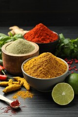 Different aromatic spices, lime and herbs on black background, closeup