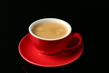 Red cup with coffee on black background, closeup