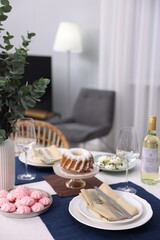 Festive table setting with dishware, desserts, wine and glasses indoors