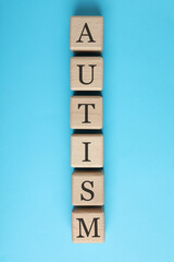 Word Autism made of wooden cubes on light blue background, top view