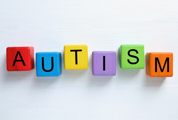 Word Autism made of colorful cubes on white wooden background, top view