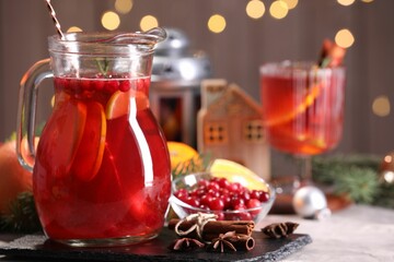 Tasty punch drink in glass jug, ingredients and Christmas decor on white table, space for text