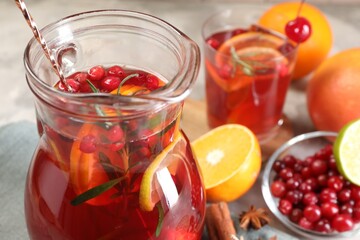 Tasty punch drink in glass jug and ingredients on table, closeup