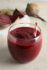 Fresh beetroot smoothie in glass on grey textured table, closeup