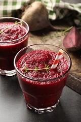 Fresh beetroot smoothie in glasses on grey textured table, closeup