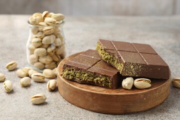 Pieces of Dubai chocolate bar with pistachios and knafeh on grey table, closeup