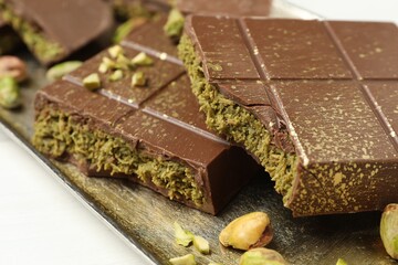 Pieces of Dubai chocolate bars with pistachios and knafeh on white table, closeup