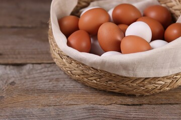 Wicker basket with fresh eggs on wooden table, closeup. Space for text