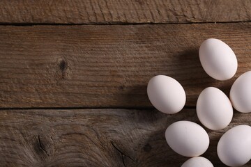 Many fresh eggs on wooden table, flat lay. Space for text
