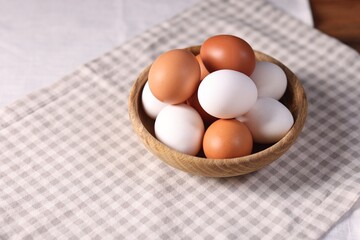 Fresh eggs in bowl on table, closeup. Space for text