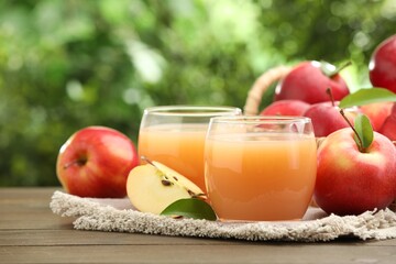 Tasty apple juice and fresh fruits on wooden table against blurred background