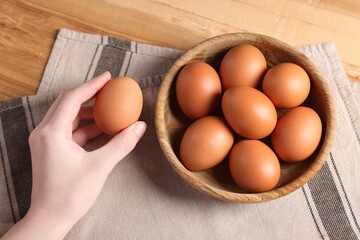 Woman with raw eggs at wooden table, top view