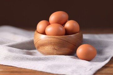 Fresh eggs in bowl on wooden table, closeup