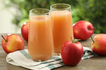 Tasty apple juice and fresh fruits on wooden table against blurred background, closeup