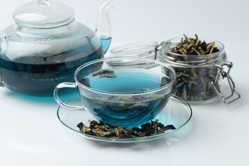 Fresh butterfly pea flower tea and dry petals on white table, closeup