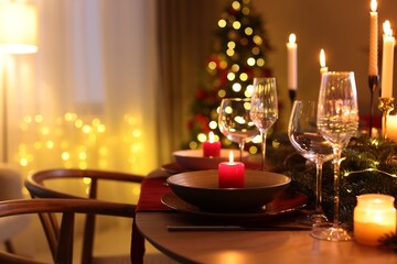 Festive table setting in room decorated for Christmas, closeup. Bokeh effect