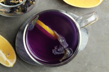 Delicious butterfly pea flower tea with lemon on gray textured table, flat lay