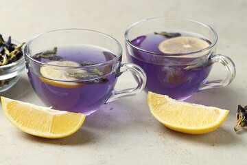Delicious butterfly pea flower tea with lemon on gray textured table, closeup