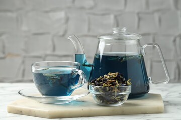 Delicious butterfly pea flower tea on white marble table against light background
