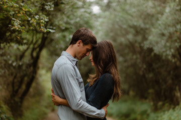 Fototapeta premium A couple sharing a sweet moment in a serene, green setting, highlighting love and connection with nature.