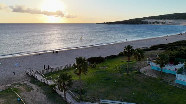 Ein kleiner Schwenk &uuml;ber den Valdevaqueros Strand in Tarifa. Der Blick zeigt die untergehende Sonne, den Ozean und den Horizont. Sanfte Wellen brechen am Ufer, w&auml;hrend der Him