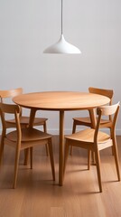 Minimalist dining room with light wood table and chairs, illuminated by a pendant lamp.