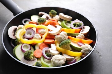 Frying pan with mix of vegetables and mushrooms on grey table, closeup