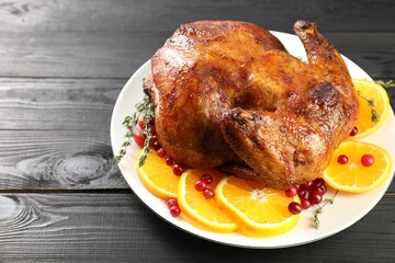 Delicious baked turkey, orange slices, cranberries and thyme on gray wooden table, closeup. Space for text