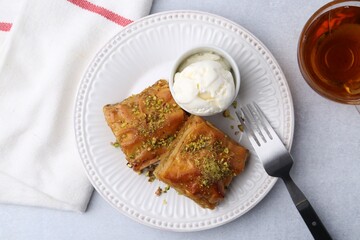 Delicious baklava with crushed nuts and ice cream served on grey table, flat lay