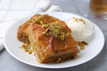 Tasty baklava with chopped nuts and scoop of ice cream on grey table, closeup