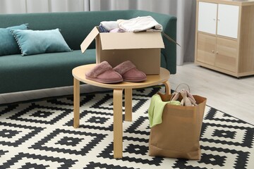 Different used clothes in box and paper bag indoors