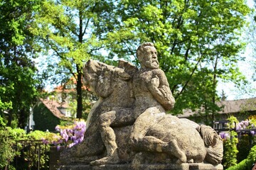 Statue of a man on a horse in a garden.