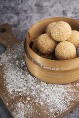 Sesame Balls Presented in a Wooden Bamboo Basket on a Rustic Wooden Board