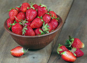 red ripe strawberries in bowl on a wooden table.