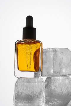 Vitamin C Serum in Glass Bottle with Ice Cube Background