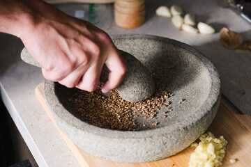Hand grinding coriander herbs with a mortar and pestle.