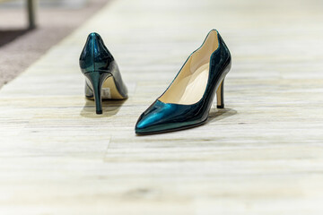 Women's model patent leather green shoes on the floor.